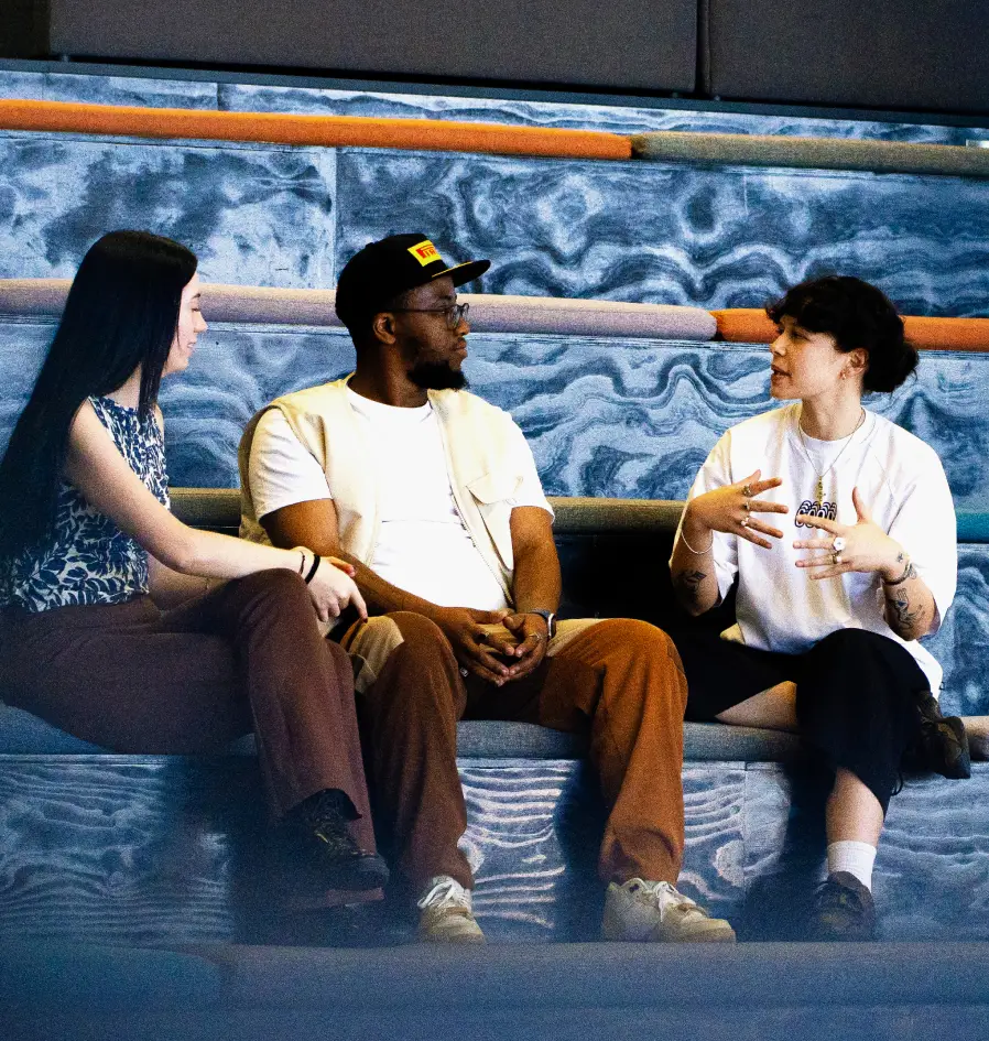 Three colleagues sitting together engaged in conversation.