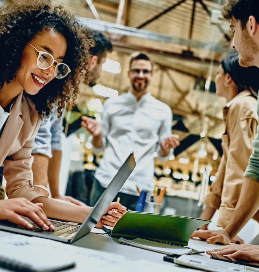 A diverse group of professionals collaborating on laptops in a modern office environment.